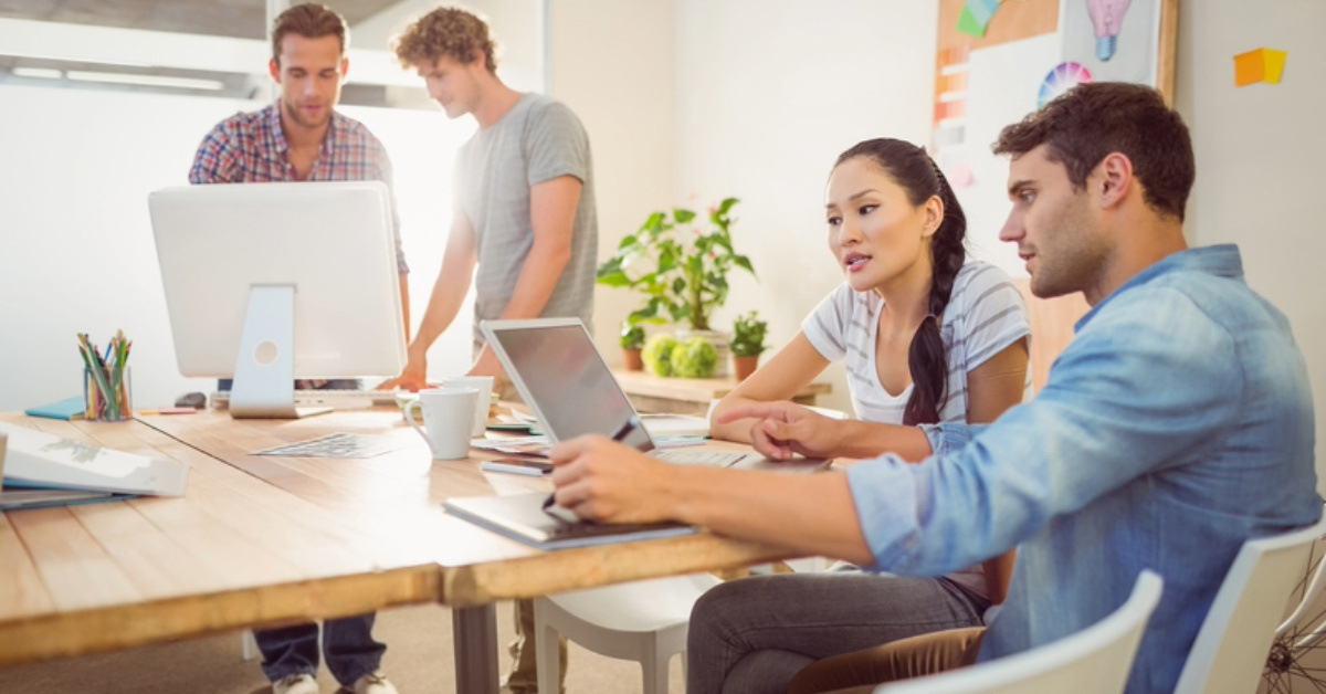 Creative business team gathered around laptops in the office 