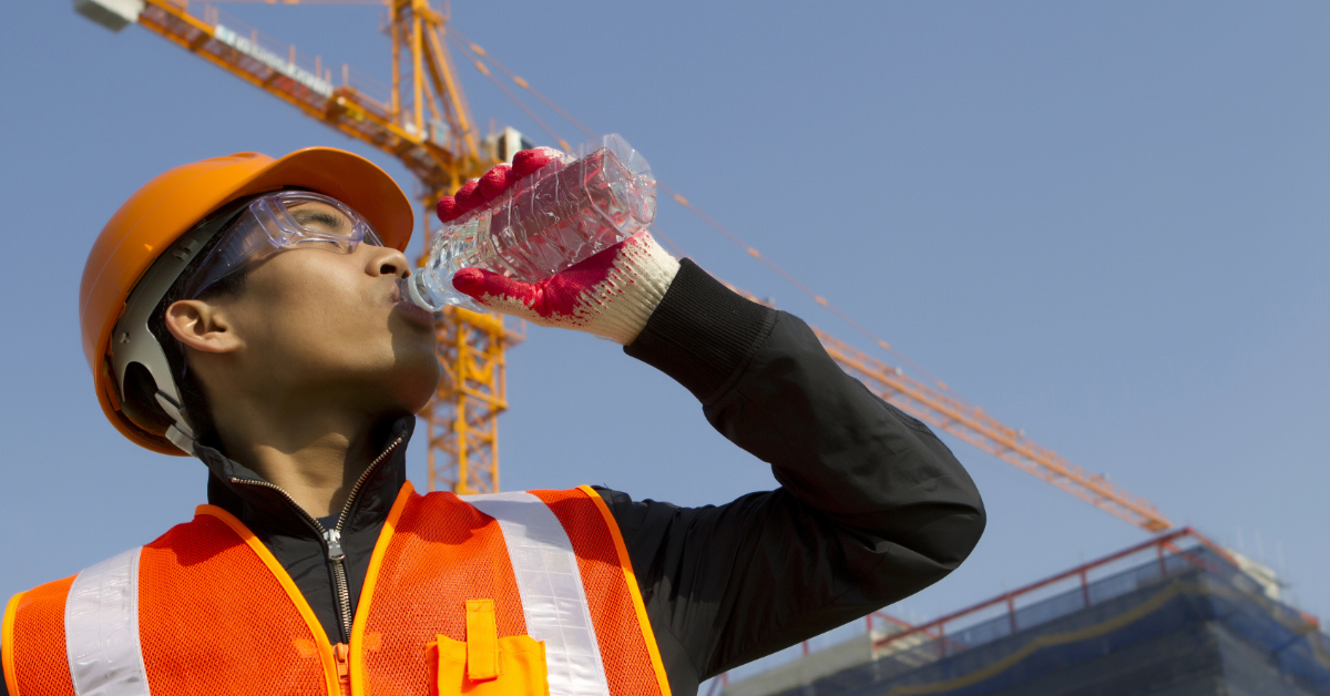 Worker man as he drinks from a plastic water bottle on construction site
